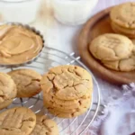 Close-up of freshly baked peanut butter cookies with a criss-cross fork pattern on a parchment-lined baking sheet