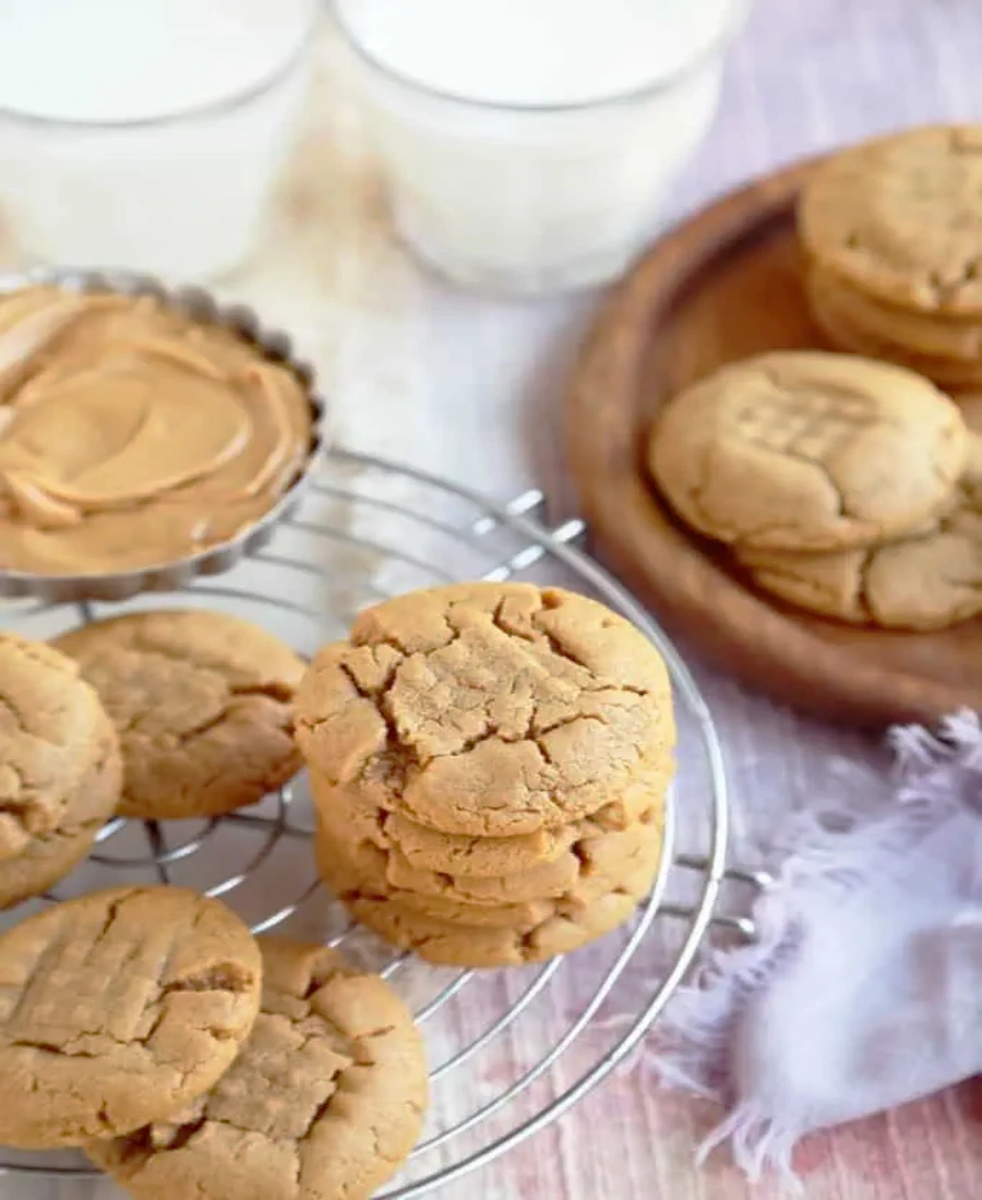 Close-up of freshly baked peanut butter cookies with a criss-cross fork pattern on a parchment-lined baking sheet