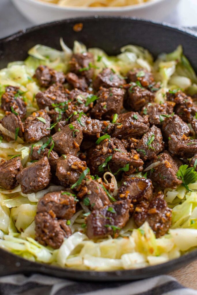 Garlic Butter Steak Bites 2 Garlic Butter Steak Bites served with sautéed cabbage and lemon